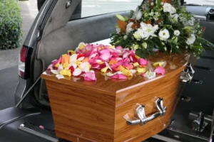 Caixão com flores sendo transportado em carro funerário.